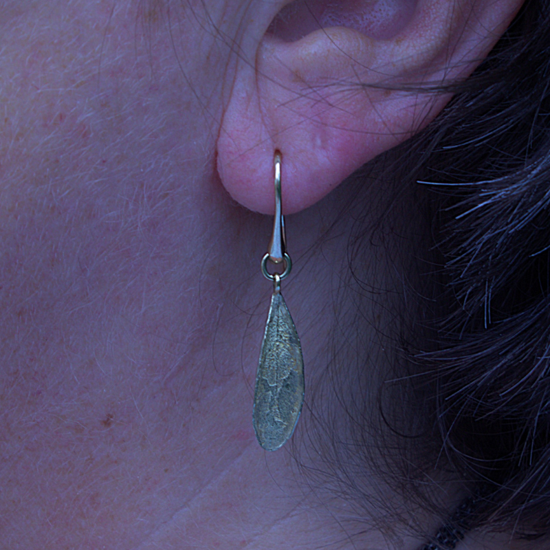 Lange gouden oorhaken met olijfblad natuurlijke textuur foto op model handgemaakt design door Goudsmederij Goedbloed