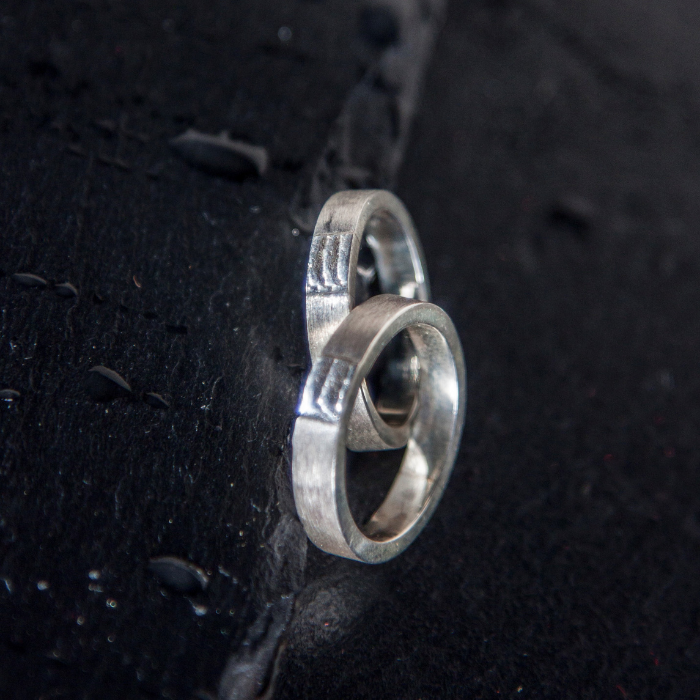 Klassieke trouwringen met een zandgegoten zee textuur als tussenstuk handgemaakt door Goudsmederij Goedbloed