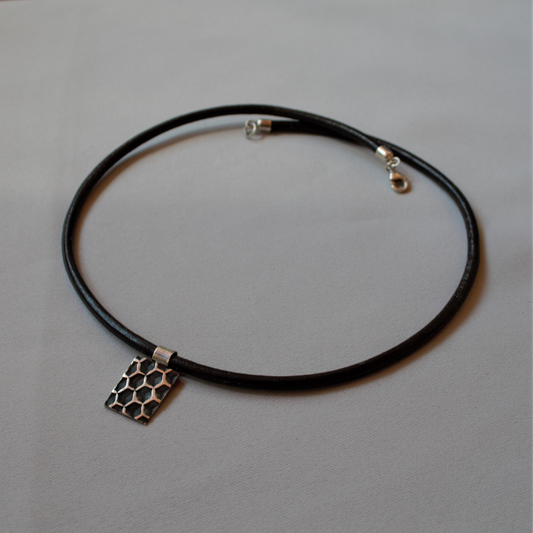 Zilveren tag hanger het Honingraatstructuur aan zwart leren koord.