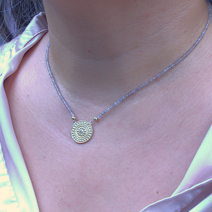 Gouden dragonstail munt met witte diamant geschakeld tussen een fijn facetgeslepen labradoriet snoer. handgemaakt door Goudsmederij Goedbloed foto op model