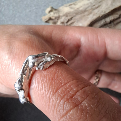 Een van zilver gevormd elvenbankje dat speels over de vinger golft als vloeibaar lava. Handgemaakt en duurzaam ontwerp door Goudsmederij Goedbloed