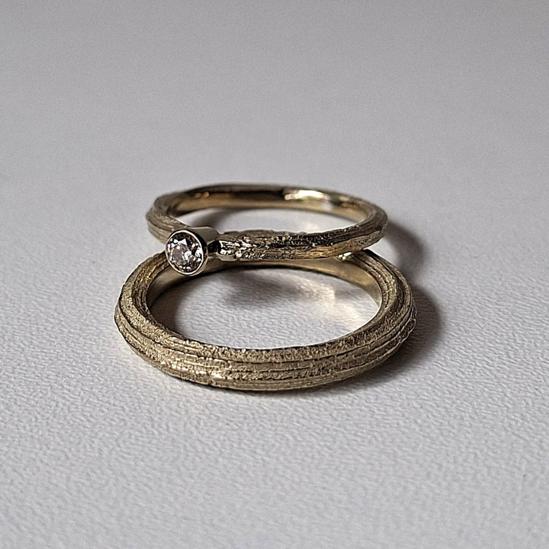 Organische minimalistische luxe Forest trouwringen met de lange textuur van Angelica, de dames ring heeft een bruine diamant solitaire rondomzetting. Handgemaakt bewust  design door Goudsmederij Goedbloed