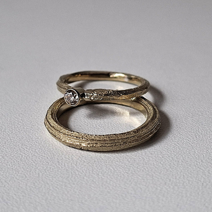 Organische minimalistische luxe Forest trouwringen met de lange textuur van Angelica, de dames ring heeft een bruine diamant solitaire rondomzetting. Handgemaakt bewust  design door Goudsmederij Goedbloed